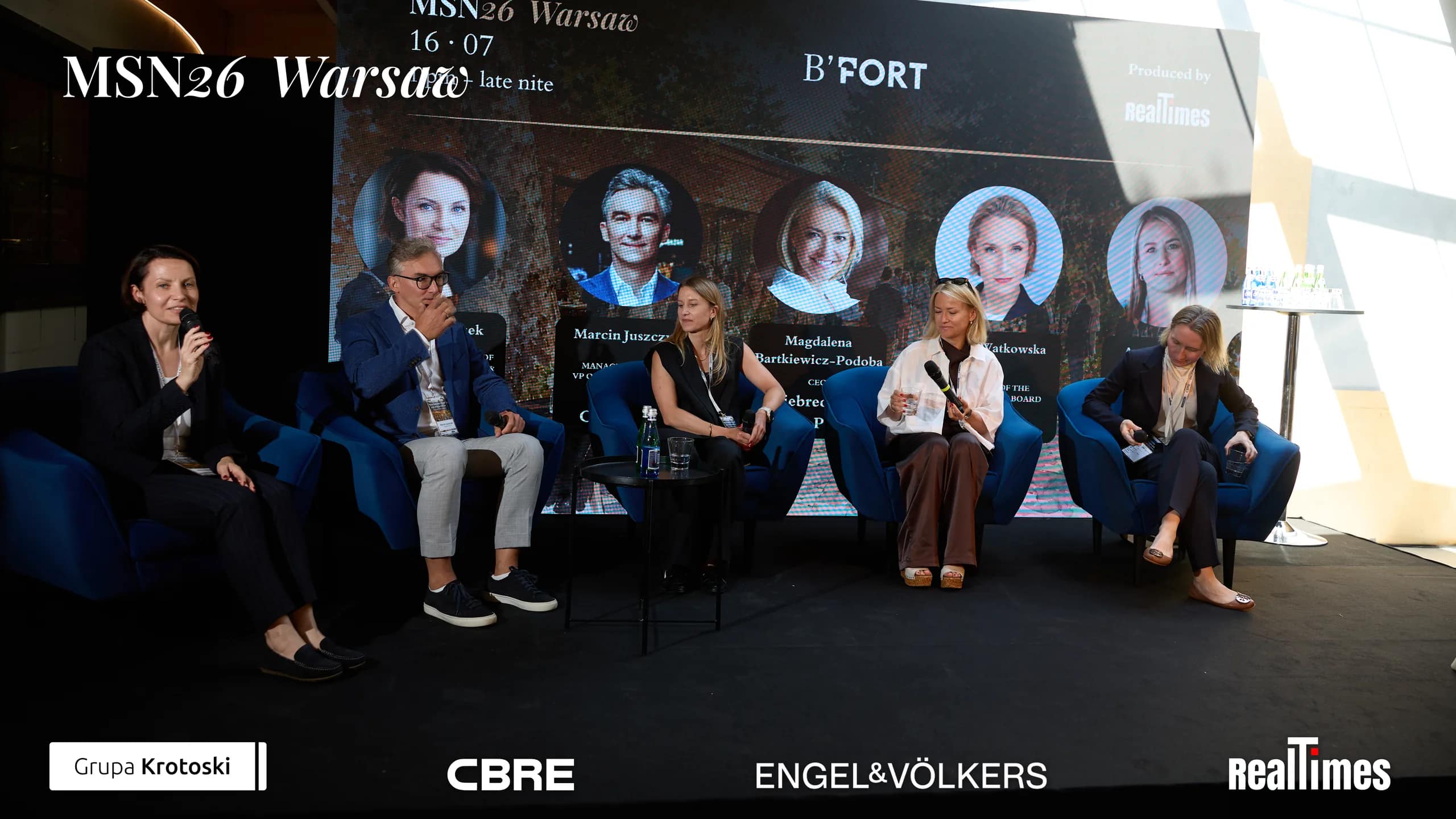 Mid-Summer Night 2026 at B'Fort, Warsaw: 5 panelists in row on stage, headshot backdrop