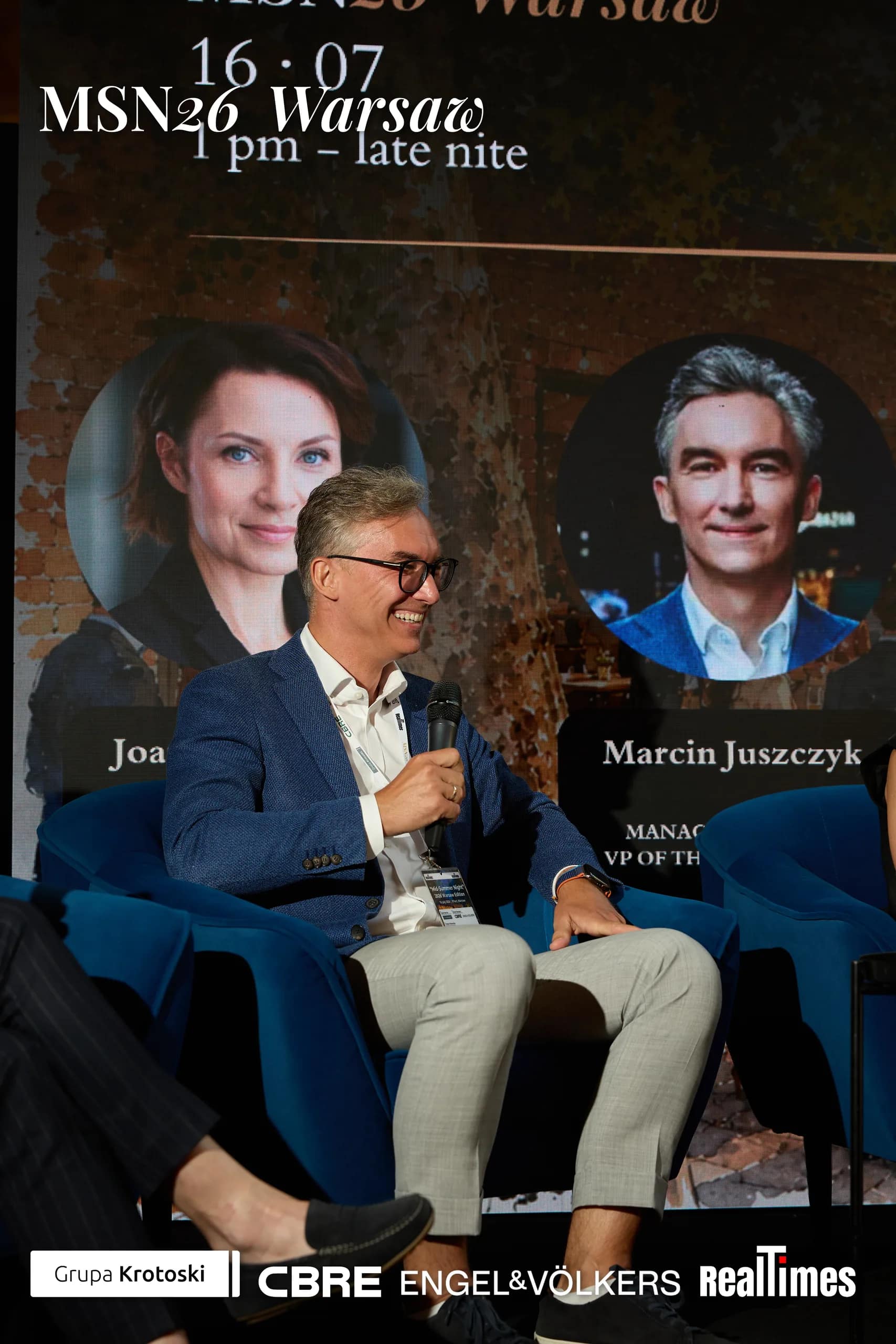 Mid-Summer Night 2026 at B'Fort, Warsaw: panelist speaking, Mroczek/Juszczyk cards
