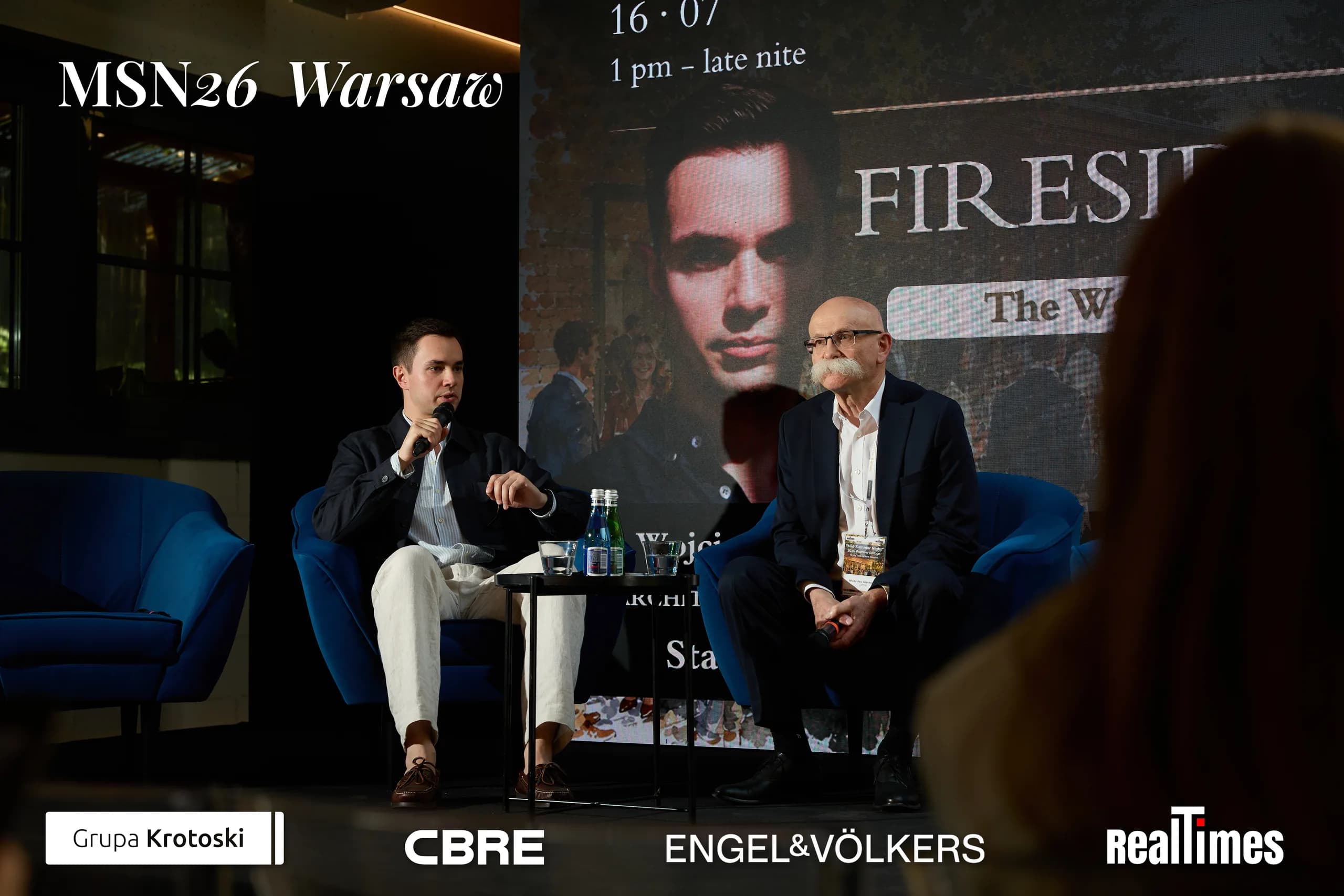 Mid-Summer Night 2026 at B'Fort, Warsaw: Fireside screen, two seated in armchairs