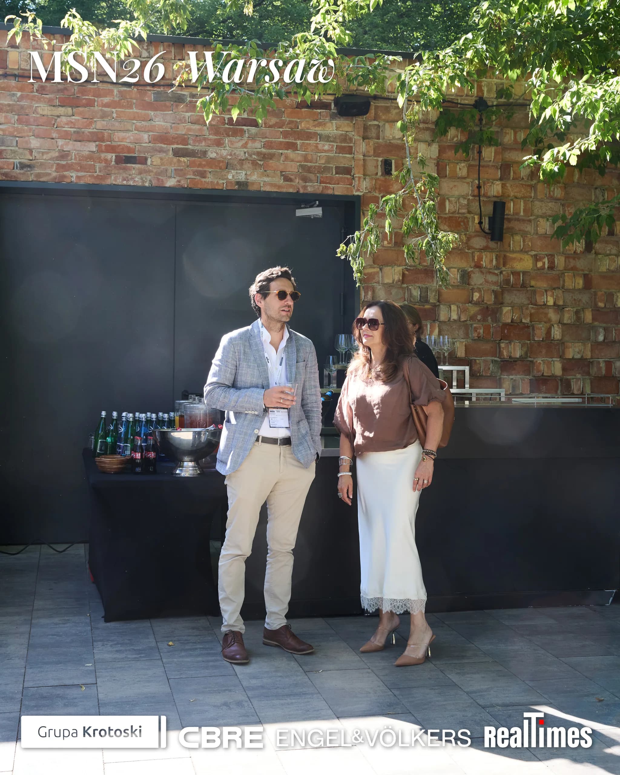 Mid-Summer Night 2026 at B'Fort, Warsaw: couple by garden bar, drinks, brick wall
