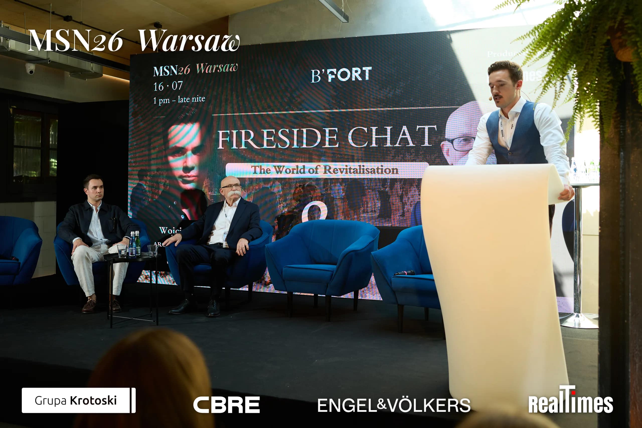 Mid-Summer Night 2026 at B'Fort, Warsaw: Fireside Chat screen, two seated plus lectern intro