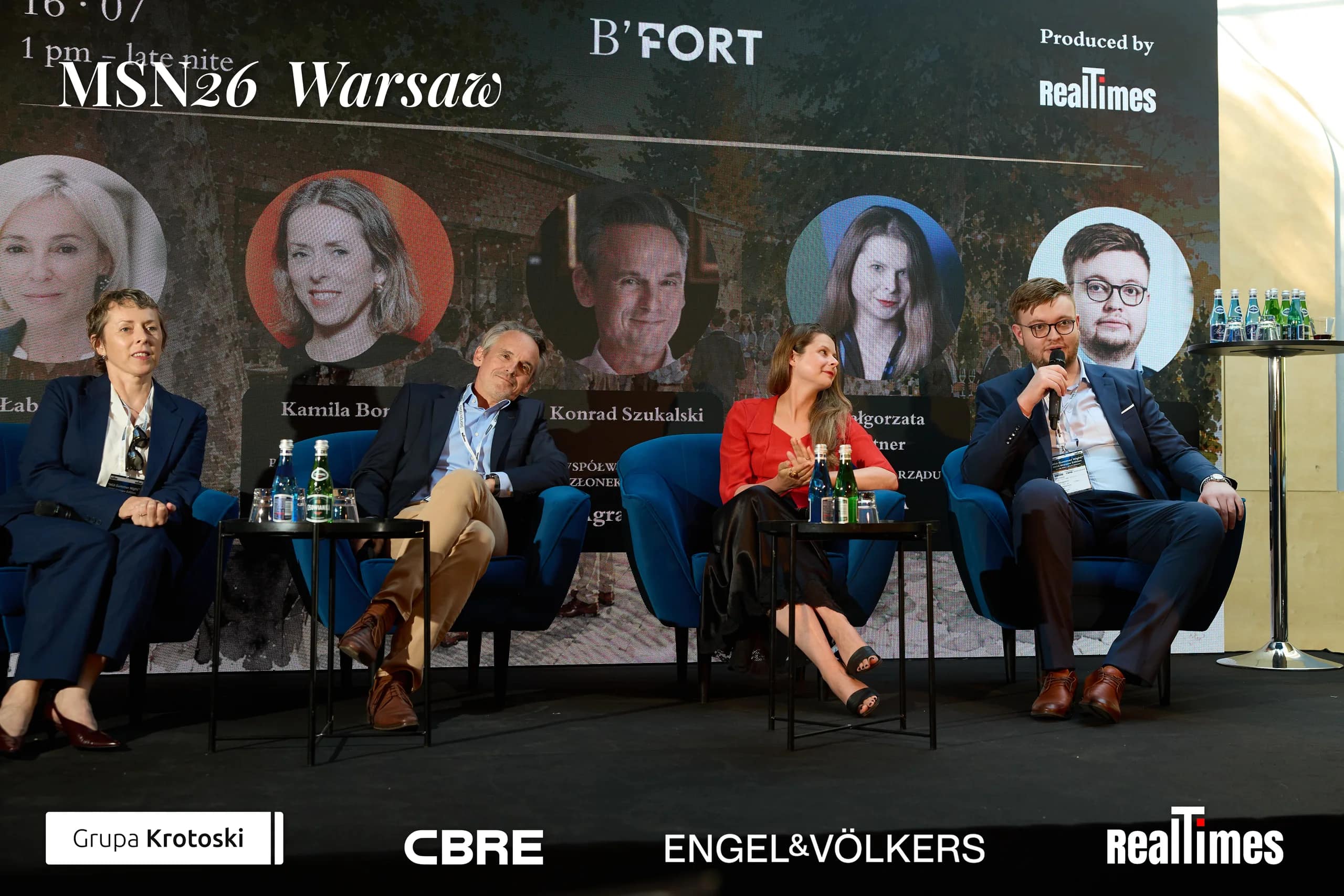 Mid-Summer Night 2026 at B'Fort, Warsaw: panelists row, headshot screen behind