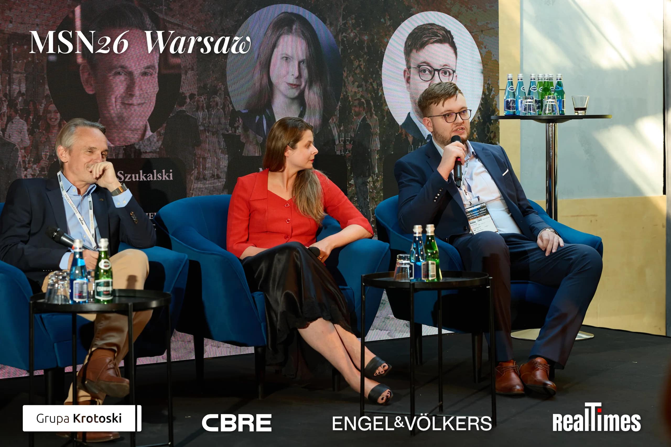 Mid-Summer Night 2026 at B'Fort, Warsaw: three panelists, man with mic