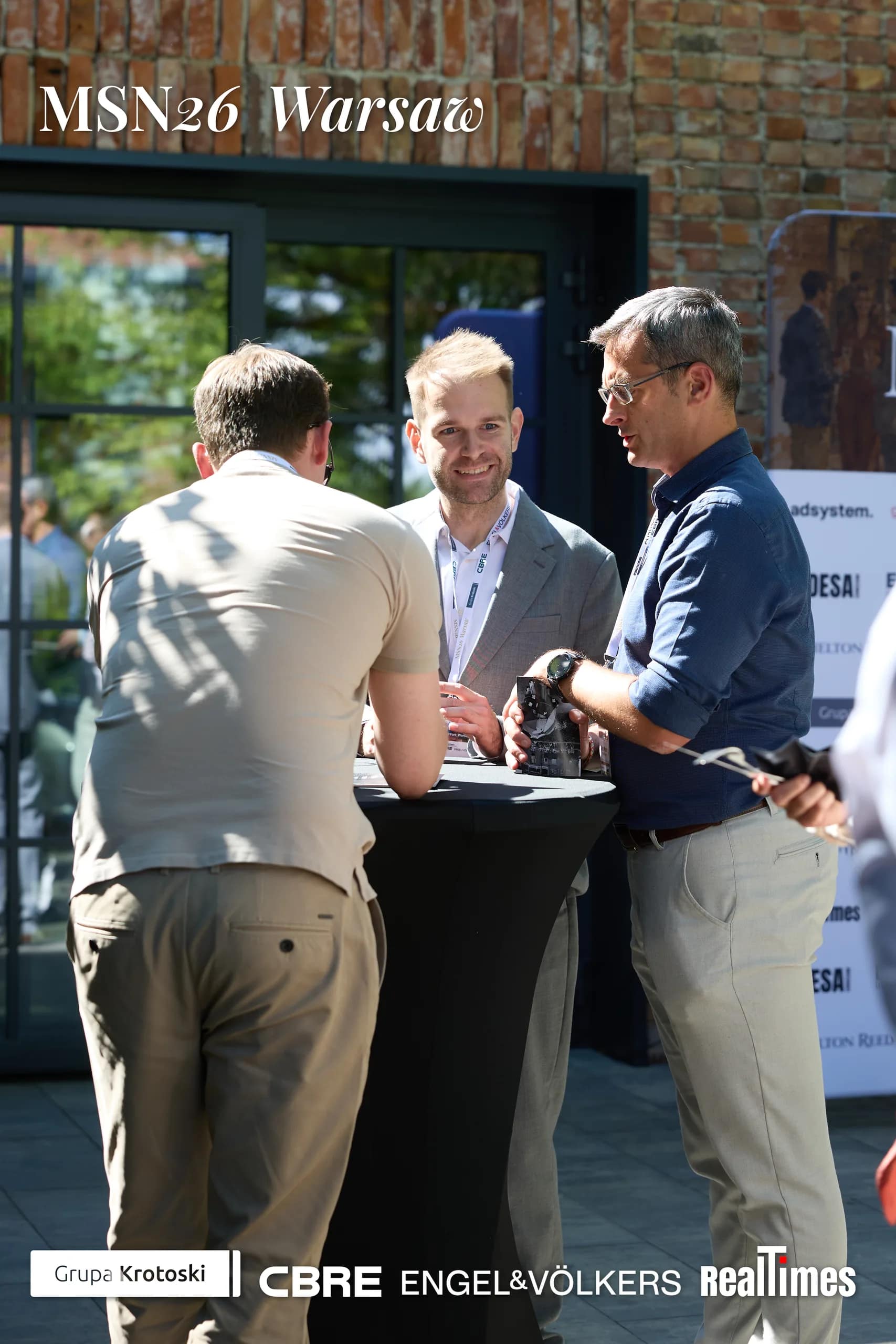 Mid-Summer Night 2026 at B'Fort, Warsaw: three men networking outdoors at table