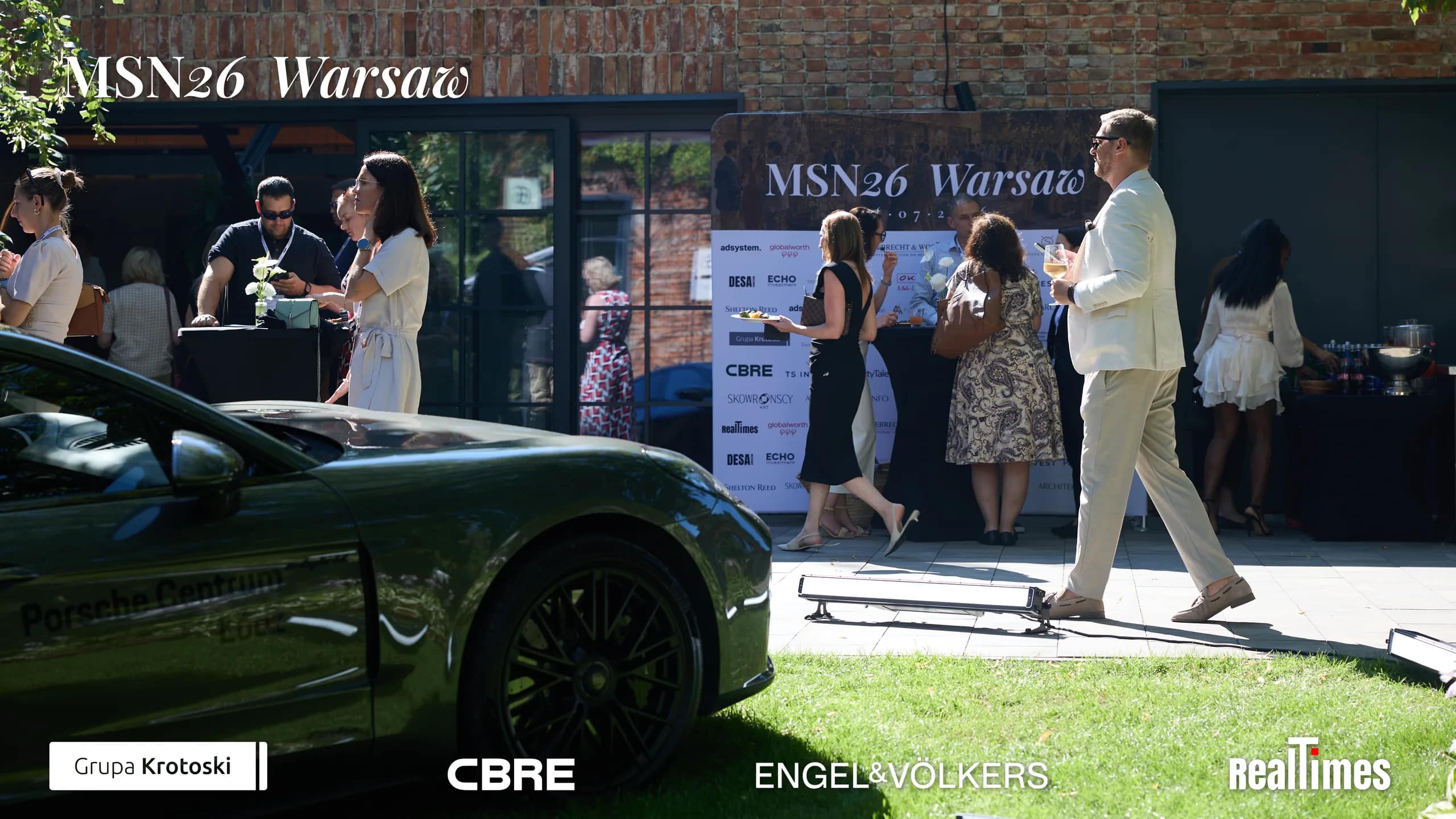 Mid-Summer Night 2026 at B'Fort, Warsaw: crowd networking by Porsche display outdoors