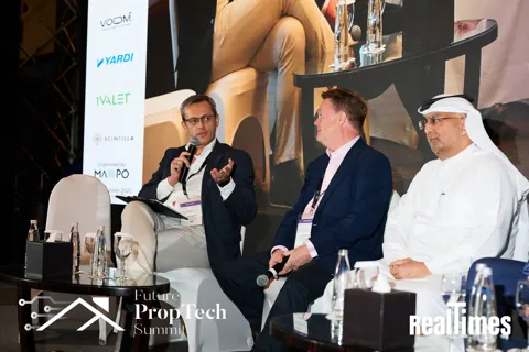 Alexander Morari moderating a panel with a microphone at Future PropTech Summit 2025 in Dubai.