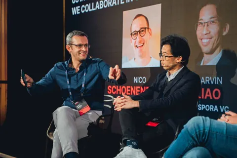 Alexander Morari smiling and gesturing towards a panellist at Engaged Investments 2024 in Prague.