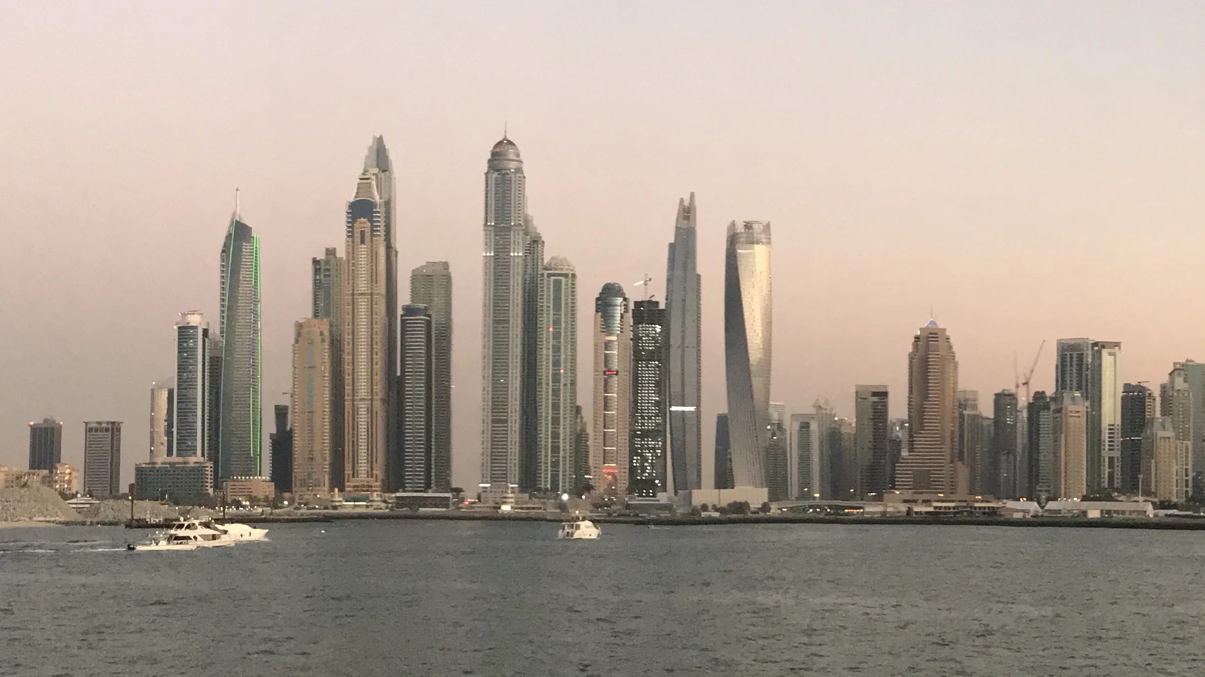 Dubai Marina towers at dusk across open water, the skyline of a city that private wealth and new firms are moving to