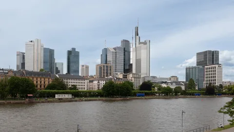 Frankfurt's banking-district towers above the River Main, seen from the Holbeinsteg footbridge on an overcast day.