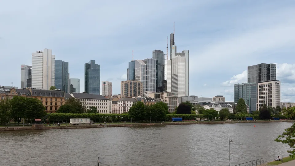 Frankfurt's banking-district towers above the River Main, seen from the Holbeinsteg footbridge on an overcast day.