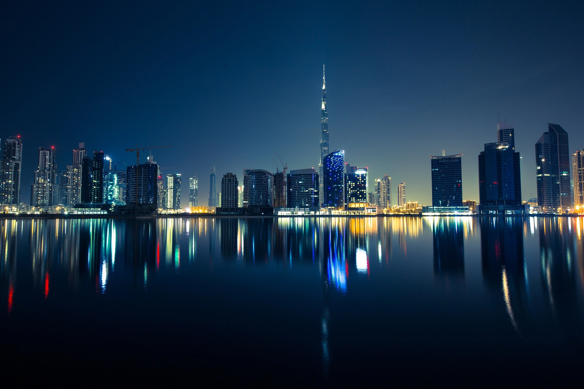 Dubai business district skyline at night, reflected in the water