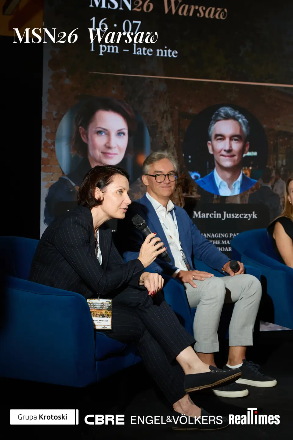 Mid-Summer Night 2026 at B'Fort, Warsaw: panelist speaking with mic, panel backdrop
