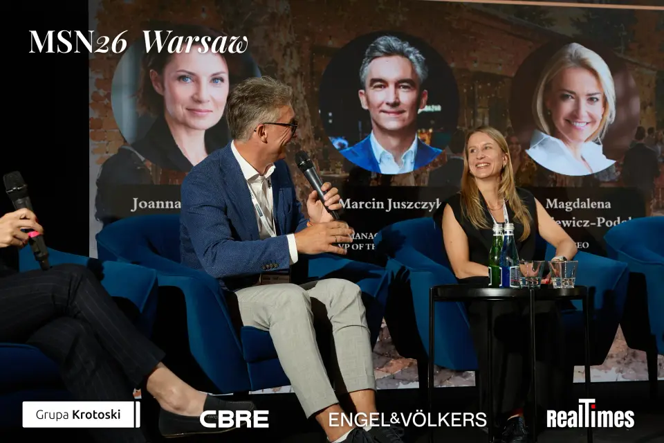 Mid-Summer Night 2026 at B'Fort, Warsaw: man with mic + panelist, speaker cards