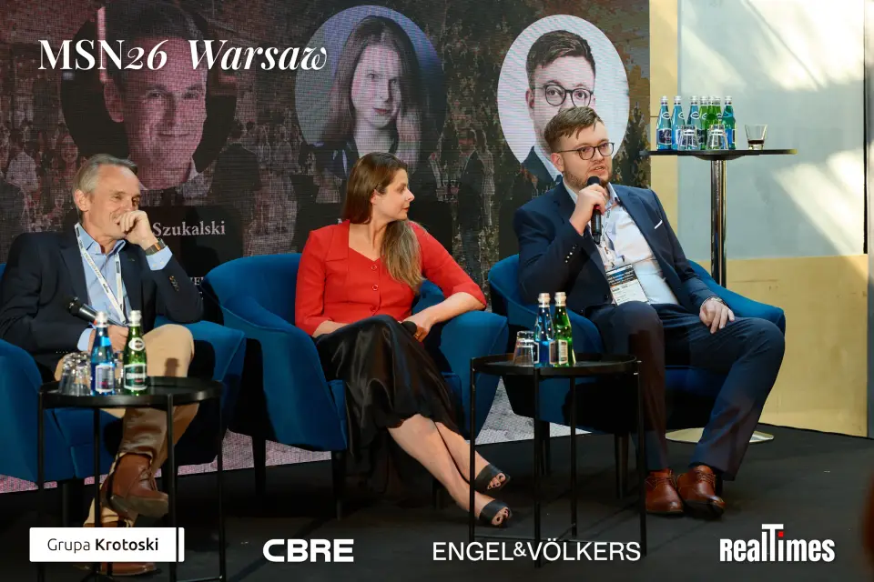 Mid-Summer Night 2026 at B'Fort, Warsaw: three panelists, man with mic