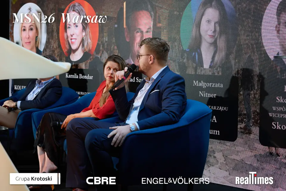 Mid-Summer Night 2026 at B'Fort, Warsaw: panelists with mic, Nitner on screen
