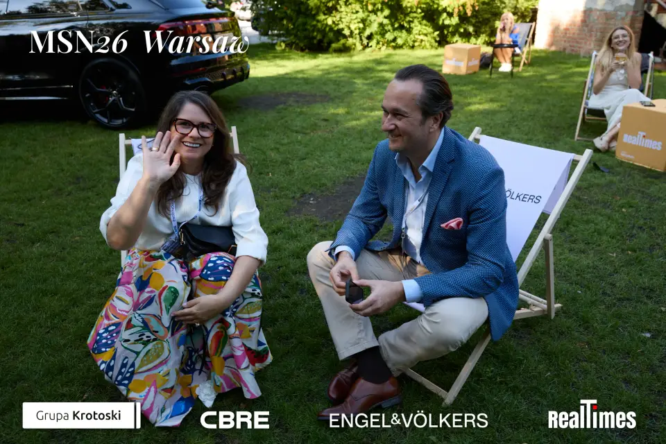 Mid-Summer Night 2026 at B'Fort, Warsaw: same pair laughing in garden deckchairs