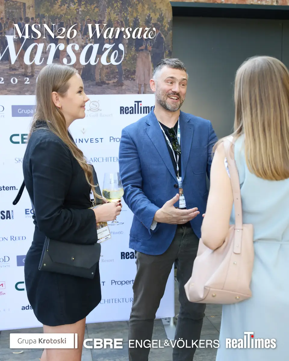 Mid-Summer Night 2026 at B'Fort, Warsaw: group chatting by sponsor backdrop, networking