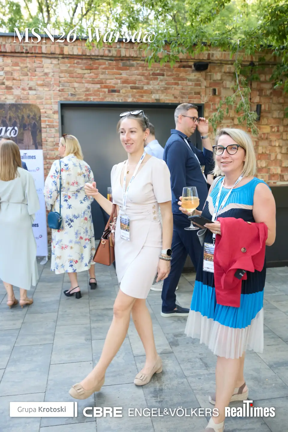 Mid-Summer Night 2026 at B'Fort, Warsaw: women walking with drinks, garden mingling